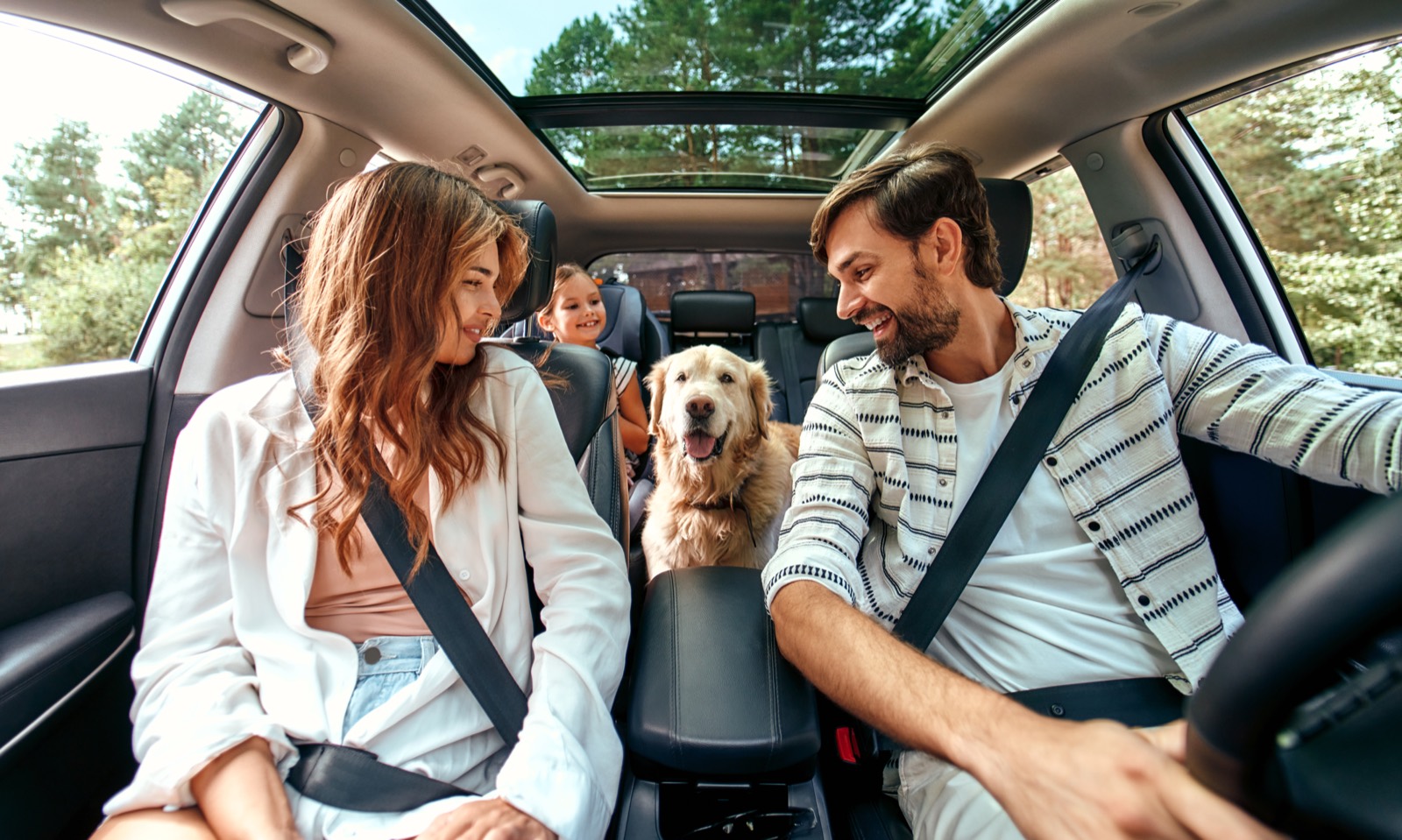 A family heading out on a trip with their golden retriever